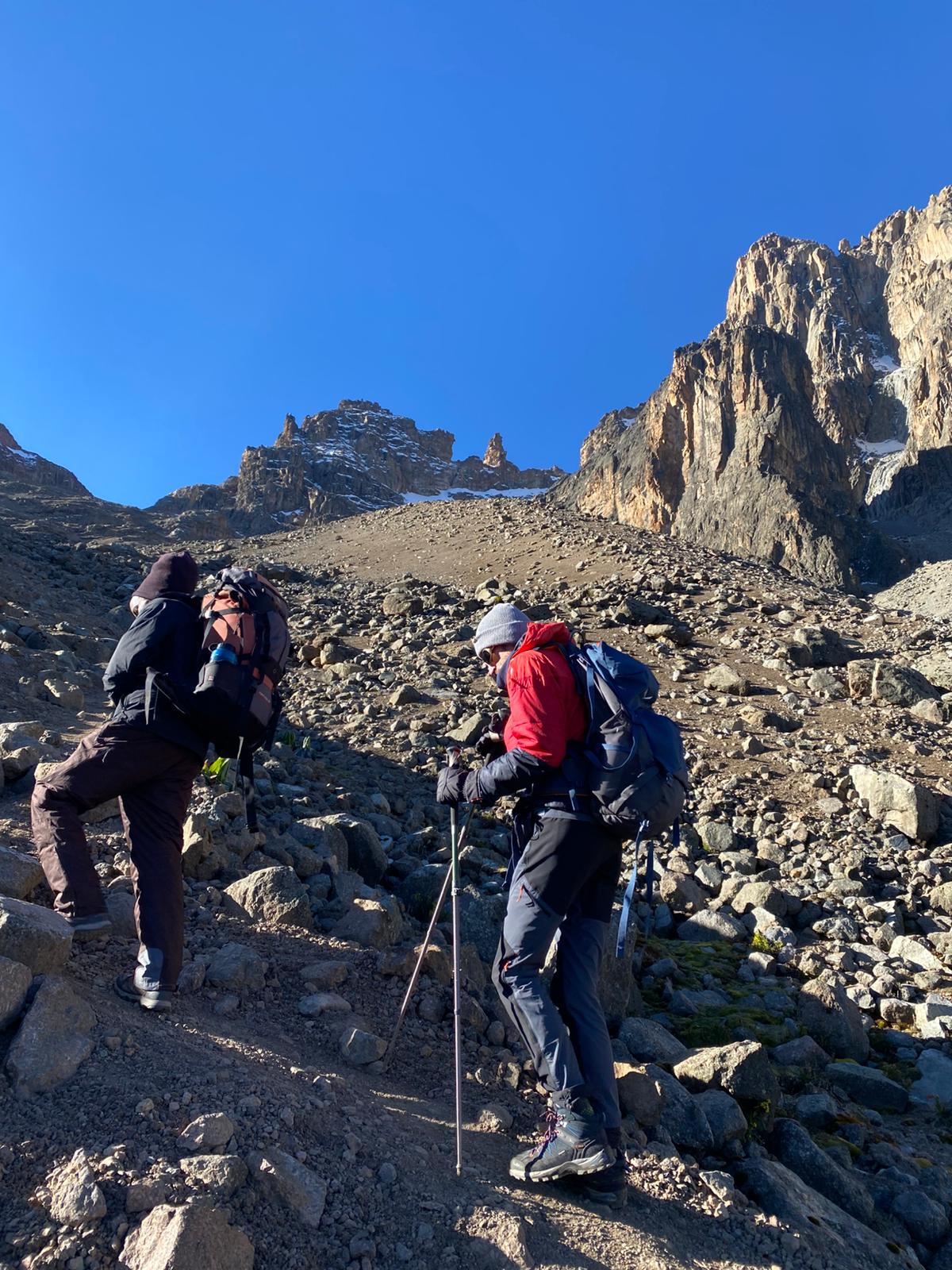 Trekkers walking across Mount Kenya alpine terrain on a beginner climb